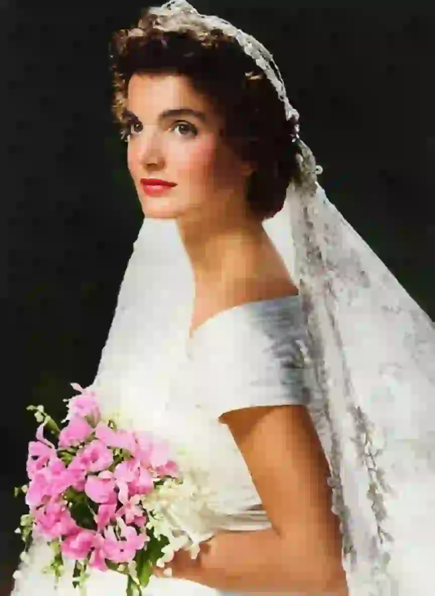 Color photo of Jacqueline in her wedding dress, holding a bouquet of flowers.